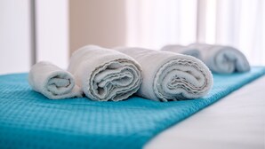 A neatly made bed with rolled white towels and a blue bedspread. - Room 'Catania' with Balcony, Wi-Fi and Air Conditioning (Giardini Naxos)