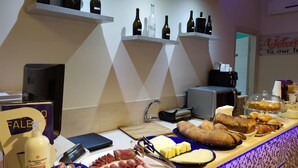 Een buffetopstelling met diverse gerechten, een spoelbak en planken met flessen.