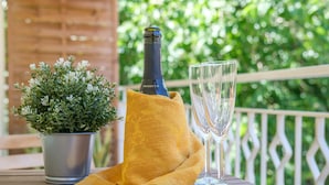 Een fles prosecco, twee glazen en een potplant op een buitentafel.