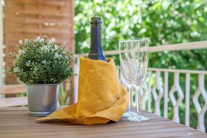 A bottle of Prosecco, two glasses, and a potted plant on an outdoor table.