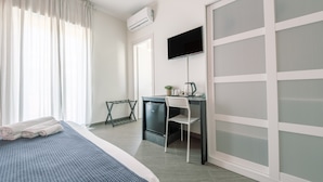 Een hotelkamer met een bed, een bureau met stoel, een televisie en een kledingkast.