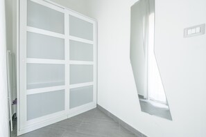 Un coin de pièce avec une porte coulissante blanche, une petite fenêtre et un interrupteur sur le mur.