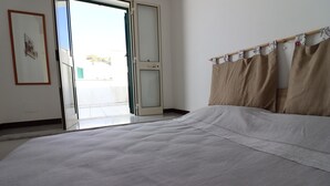 Une chambre à coucher avec un lit, une porte-fenêtre coulissante et un rideau.