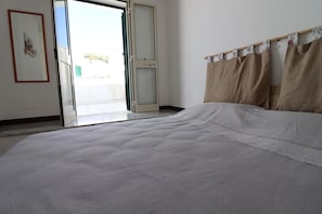 Une chambre à coucher avec un lit, une porte-fenêtre coulissante et un rideau.