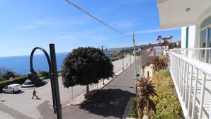 Une rue côtière avec un passage piéton, un fourgon blanc et un immeuble doté d’un balcon donnant sur la mer.