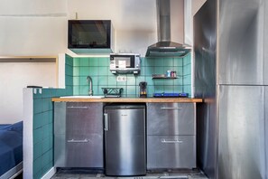 Une cuisine compacte équipée d’un four à micro-ondes, d’un grille-pain et d’un petit réfrigérateur.