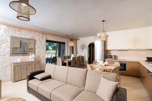 Una sala de estar moderna con sofá, mesa de comedor y zona de cocina con armarios y electrodomésticos.