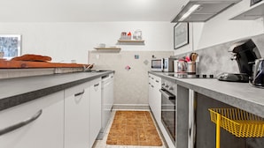 Una cocina moderna con armarios blancos, un microondas, un hervidor y una cafetera.