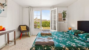 Un dormitorio con cama, una silla, una mesa y vistas al exterior.