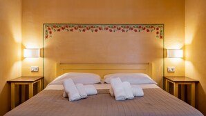 Una habitación de hotel con una cama, dos mesitas de noche y lámparas.
