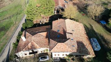 An aerial view of a house with a tiled roof, a garage, and a driveway.