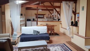 A cozy room with a bed, a small table, a sofa, and a kitchen area in the background. - Holiday Home 'Pey Sud' with Mountain View, Private Terrace and Wi-Fi (Sistels)