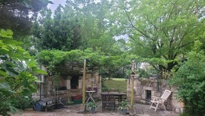 A rustic outdoor patio with a stone structure, a table, chairs, and potted plants. - Holiday Home 'Pey Sud' with Mountain View, Private Terrace and Wi-Fi (Sistels)