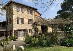 A stone building with wooden shutters, a covered porch, and a garden with various plants. - Apartment "Familha" with Mountain View, Private Terrace and Wi-Fi (Sistels)