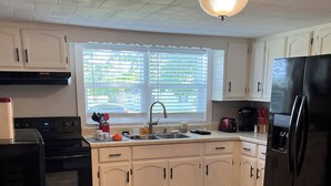 A kitchen with white cabinets, a black refrigerator, a stove, and a sink. - Cozy modern farmhouse w/ garage- Only 5 miles to Lake Cumberland! (Monticello)