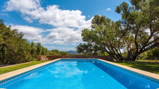 A rectangular swimming pool with clear blue water, surrounded by a stone wall and lush greenery. - Country House 'Sa Caseta' with Mountain View, Private Pool and Wi-Fi (Artà)