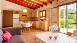 A cozy interior with a dining area, kitchen, and a sofa with a cushion. - Country House 'Sa Caseta' with Mountain View, Private Pool and Wi-Fi (Artà)