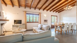 Una sala de estar con sofá, televisor, mesa de comedor y sillas.