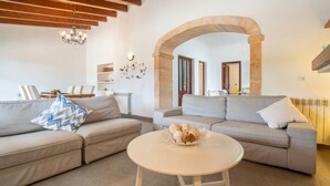 Una sala de estar moderna con dos sofás, una mesa de centro y un arco que conduce a otra habitación.
