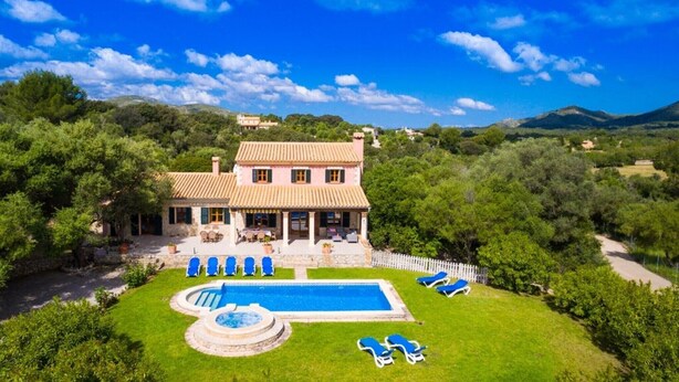 A villa with a swimming pool, multiple lounge chairs, and a well-maintained garden. - Country House 'Es Corto' with Mountain View, Private Pool and Wi-Fi (Illes Balears)