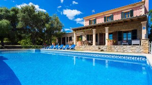 A pool with blue tiles, a stone building with columns, and a clear blue sky. - Country House 'Es Corto' with Mountain View, Private Pool and Wi-Fi (Illes Balears)