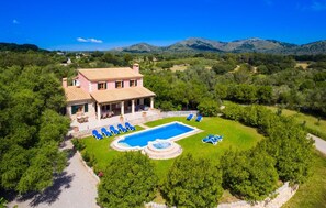 Eine Villa mit Swimmingpool, Liegestühlen und einer Terrassenanlage.