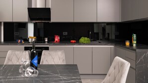 A modern kitchen with a marble countertop, a built-in oven, and a dining area with a table and chairs. - Willkommen in der Villa Nene, Ihrem Traumurlaubsparadies (Pićan)