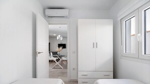 A bedroom with two beds, a wardrobe, and a dining area in the background.