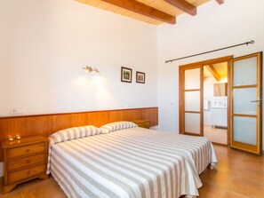 Une chambre à coucher comprenant un lit, une tête de lit en bois, des tables de chevet et une armoire avec une porte coulissante.