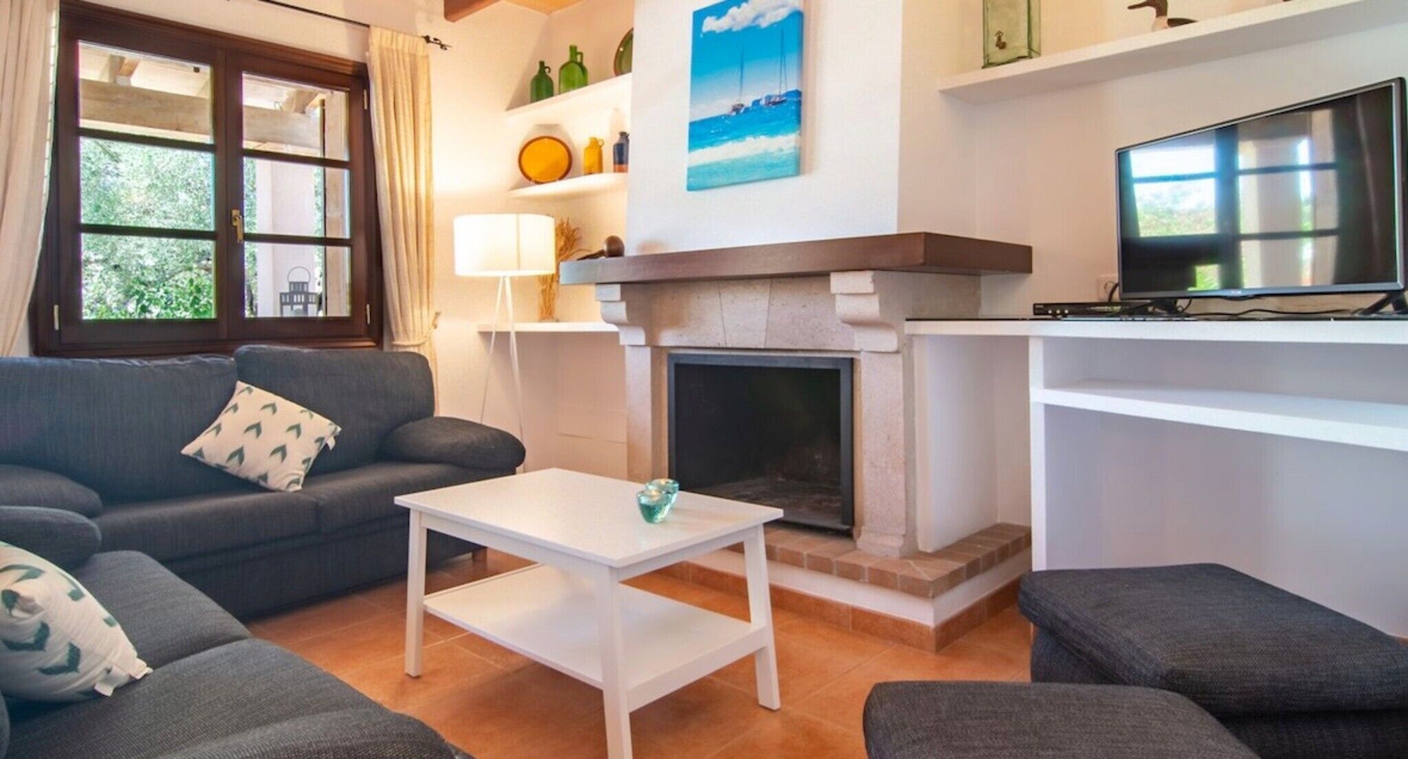 Una sala de estar con sofá, mesa de centro, chimenea y televisión.