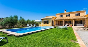 Une maison à deux étages avec une piscine, un patio doté de chaises et une pelouse bien entretenue.