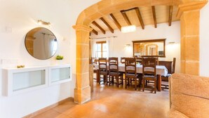 Un comedor con un espejo redondo, sillas de madera y una mesa blanca.