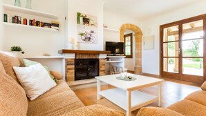Una sala de estar con chimenea, televisor, sofá y una mesa de comedor.