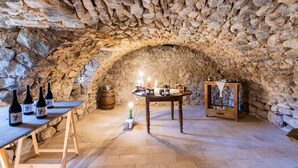 A stone-walled cellar with a wooden table holding wine bottles, a candle, and a small altar. - Room 'La Ferme De Chalas - Dénave' with Shared Pool, Shared Terrace and Wi-Fi (Valgorge)