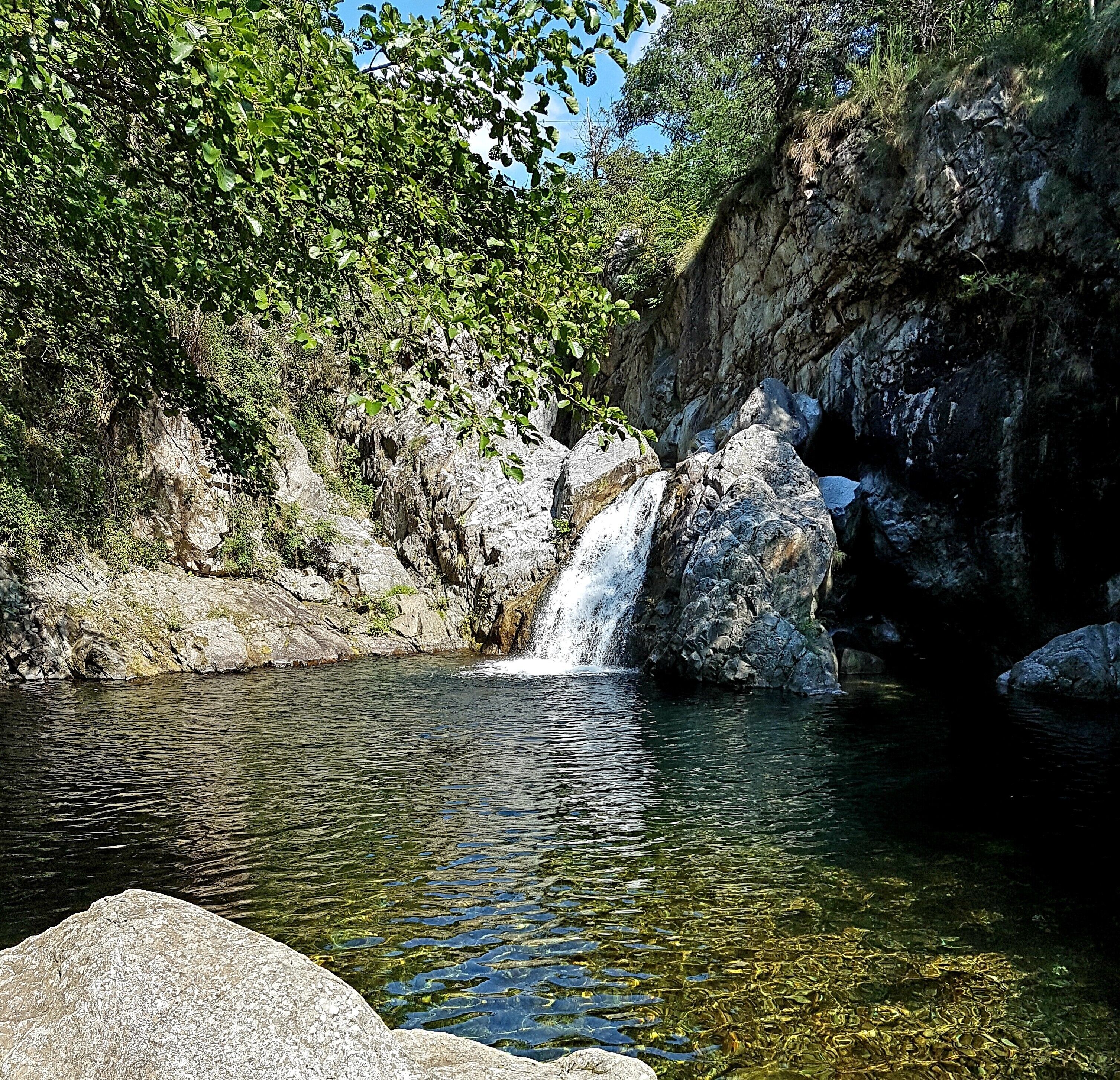 A natural water feature surrounded by rocks and greenery.
