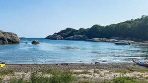 Ett lugnt kustområde med klippformationer och ett klart, blått hav.