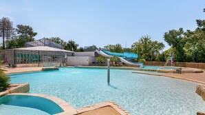 Ein Schwimmbecken mit Rutsche, überdachtem Bereich und eingezäuntem Spielplatz.