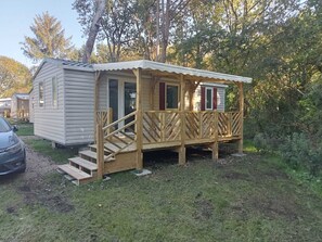 Une petite cabane en bois dotée d’une véranda et d’un escalier menant à une porte.