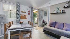 Ein Essbereich mit Tisch und Stühlen, einer Couch, einem Ventilator, einem Feuerlöscher und einer Pinwand.