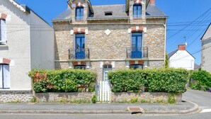 A stone building with two balconies, a central door, and a small window on the second floor. - Holiday Home 'Maison Albizia' with Private Terrace, Garden, and Wi-Fi (Le Croisic)