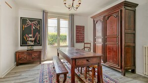 A room with a wooden table, bench, large cabinet, and artwork on the walls. - Holiday Home 'Maison Albizia' with Private Terrace, Garden, and Wi-Fi (Le Croisic)