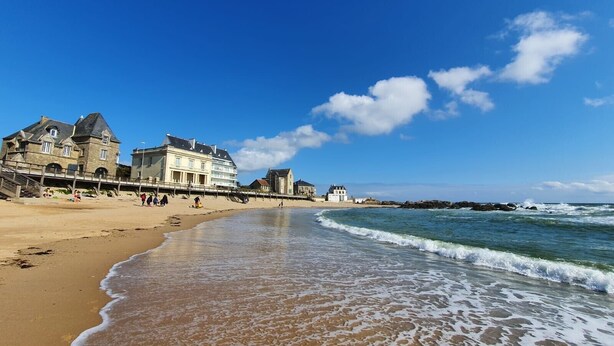 A beach with a stone building, a pier, and the ocean. - Holiday Home 'Maison Albizia' with Private Terrace, Garden, and Wi-Fi (Le Croisic)