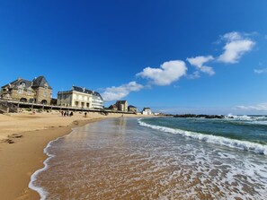 A beach with a stone building, a pier, and the ocean.