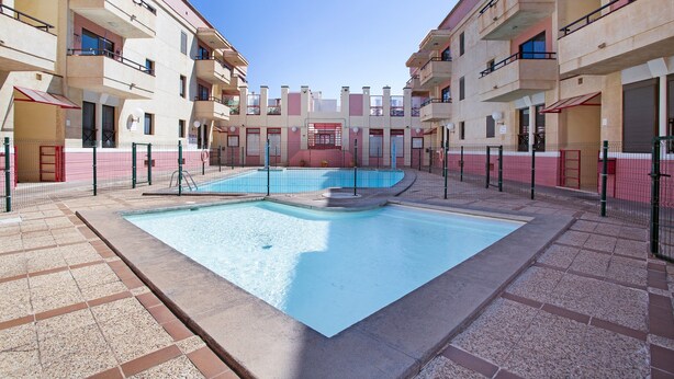 Un patio con piscina rodeado de edificios de varios pisos con balcones.