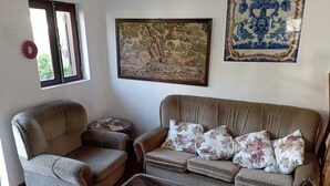 Ein Wohnzimmer mit einer Couch, einem Sessel und einem kleinen Tisch mit Papieren.