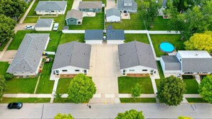 Un quartier résidentiel avec des maisons à deux étages, une piscine et une rue bordée de voitures garées.