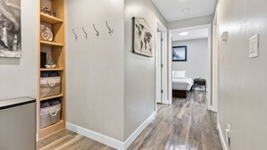 Un couloir avec un meuble de rangement en bois, un lit et une carte du monde encadrée accrochée au mur.
