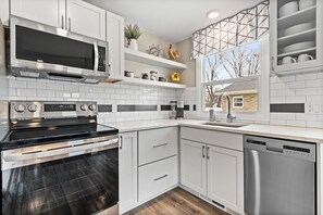 A modern kitchen with white cabinets, a stainless steel stove, and a dishwasher.