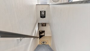 Un escalier menant à un palier orné d’une citation encadrée, d’un miroir fixé au mur et d’une porte dotée d’une fenêtre.