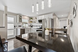 Una cocina moderna con armarios blancos, electrodomésticos de acero inoxidable y una mesa de comedor de madera oscura.